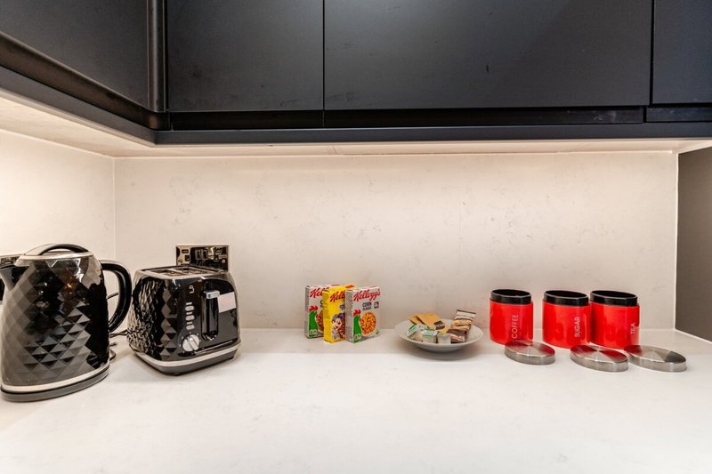 Modern kitchen counter with kettle, toaster, and red storage canisters