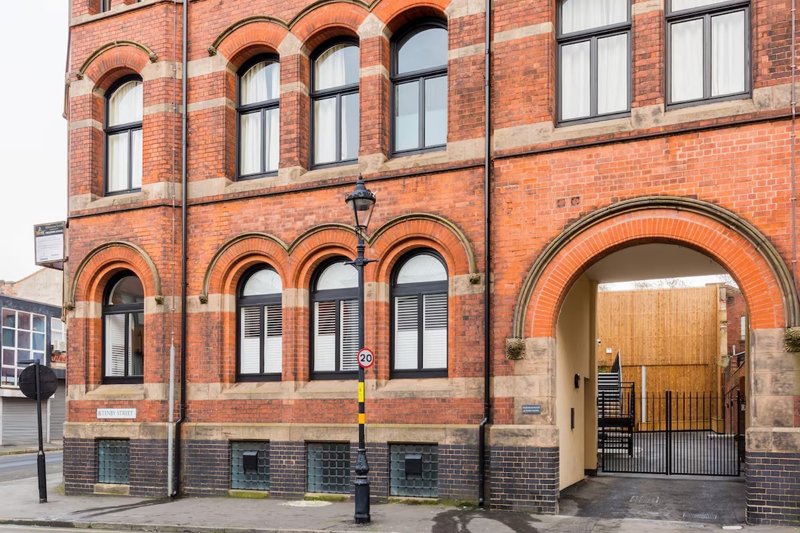 Red brick Victorian building exterior with arched windows and wooden entrance archway