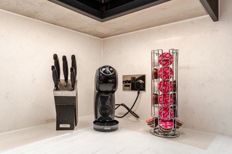 Kitchen counter with knife block, coffee maker, and pink flower stand arrangement