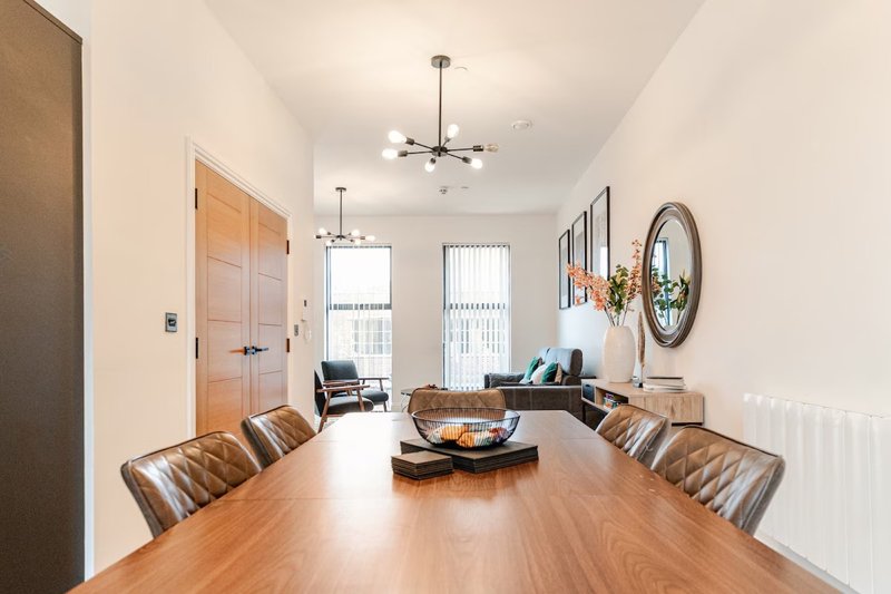 Open-plan dining and living area with wooden table, leather chairs, and contemporary furniture
