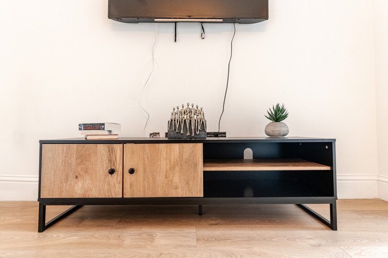 Modern living room with wooden and black TV stand, wall-mounted TV, and decorative items
