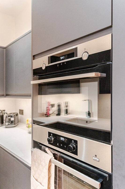 Modern kitchen with built-in stainless steel ovens, white cabinetry and minimalist design