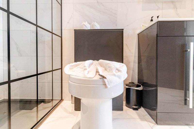 Modern bathroom with pedestal sink, glass shower enclosure, and dark vanity unit