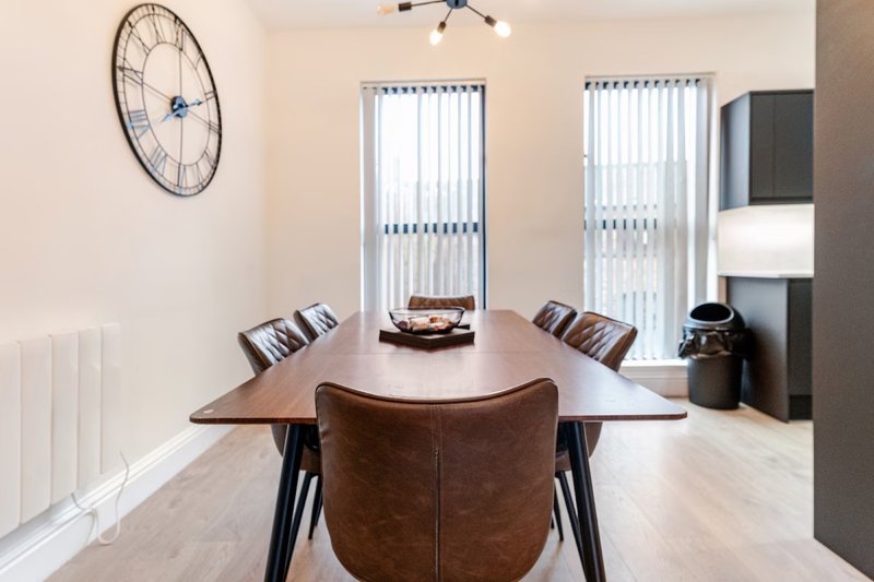 Modern dining room with wooden table, brown leather chairs, wall clock and vertical blinds