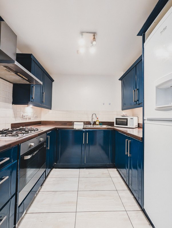 Modern kitchen with blue cabinetry, stainless steel appliances, white subway tile backsplash and tiled flooring