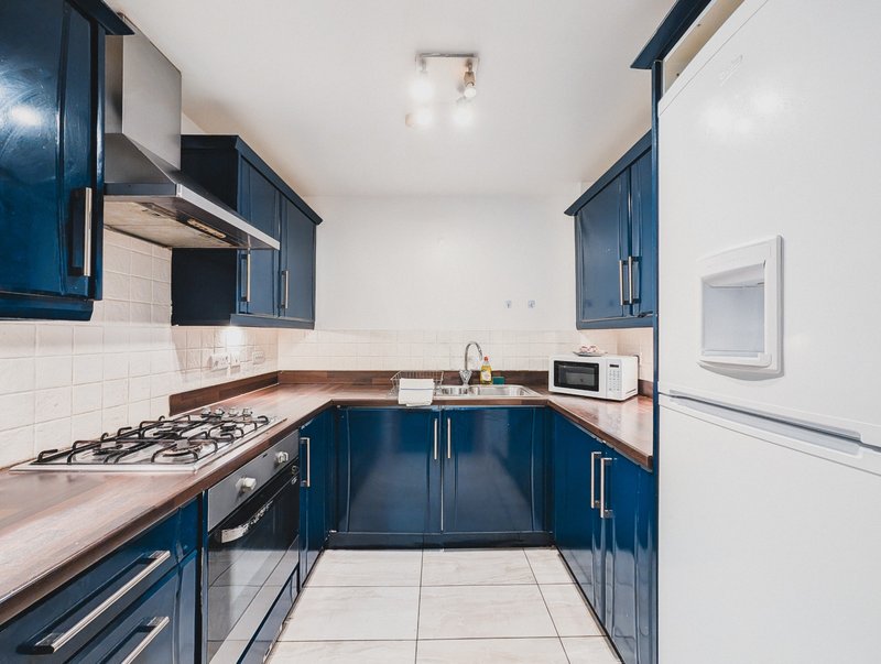 Modern kitchen with dark blue cabinetry, gas hob, sink, and wooden worktops