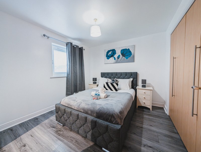 Modern bedroom with double bed, wooden floor, bedside tables and blue wall art