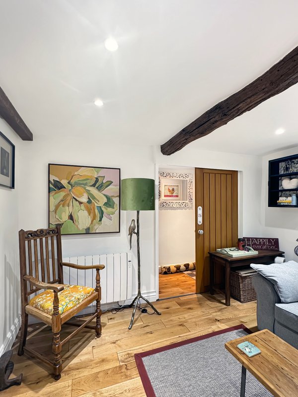 Open-plan bedroom and living area with wooden beams, wooden floors, and mix of vintage and modern furnishings
