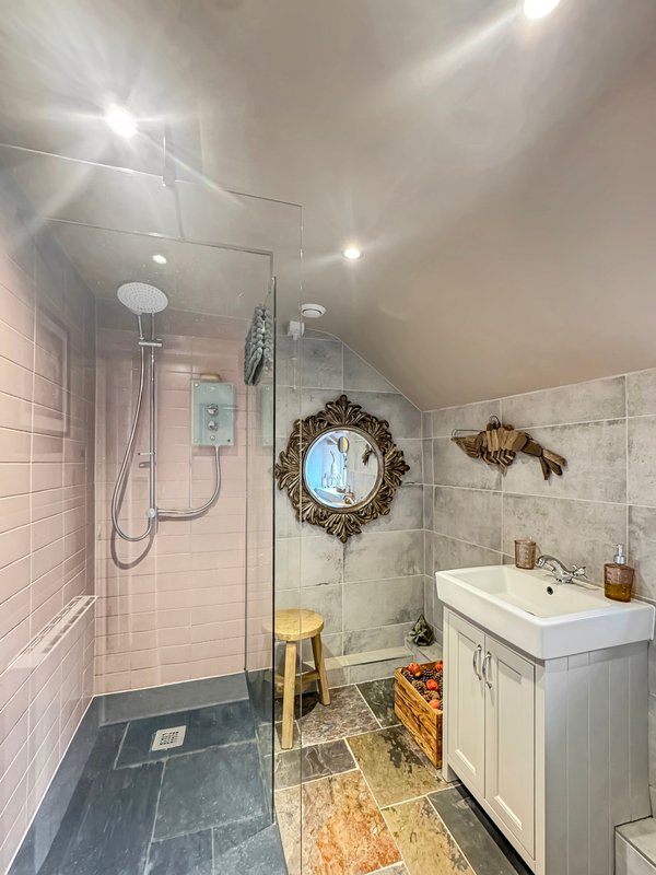 Modern bathroom with walk-in shower, white vanity, decorative mirror and pendant lighting
