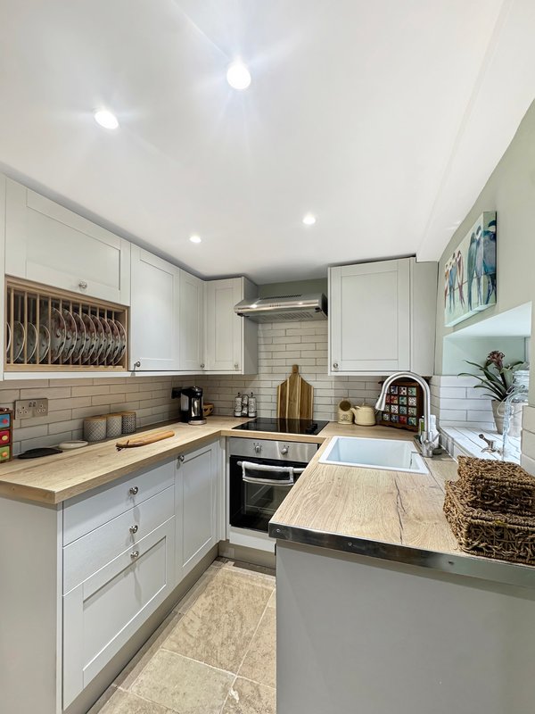 Modern kitchen with white cabinetry, wooden countertops, subway tile backsplash and island