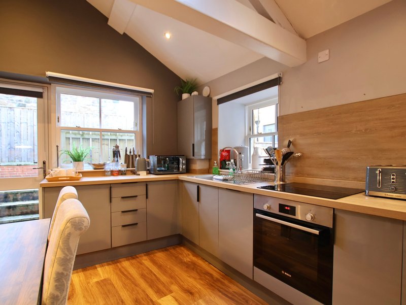 Modern kitchen with wooden countertops, stainless steel appliances, and garden views through windows