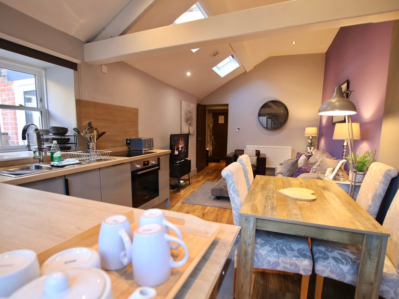 Open-plan kitchen and dining area with wooden table, chairs, and modern appliances