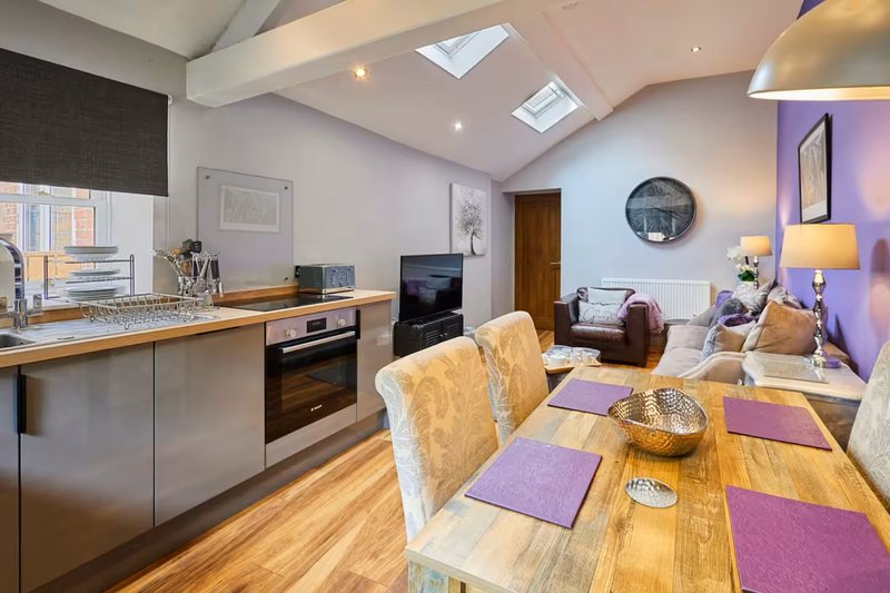 Open-plan kitchen and living area with dining table, modern appliances and skylight windows