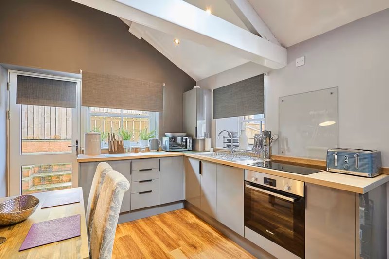 Modern kitchen with white cabinetry, wooden countertops, built-in oven, and skylight windows
