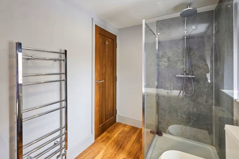 Modern bathroom with walk-in shower, heated towel rail, wooden door and wooden flooring