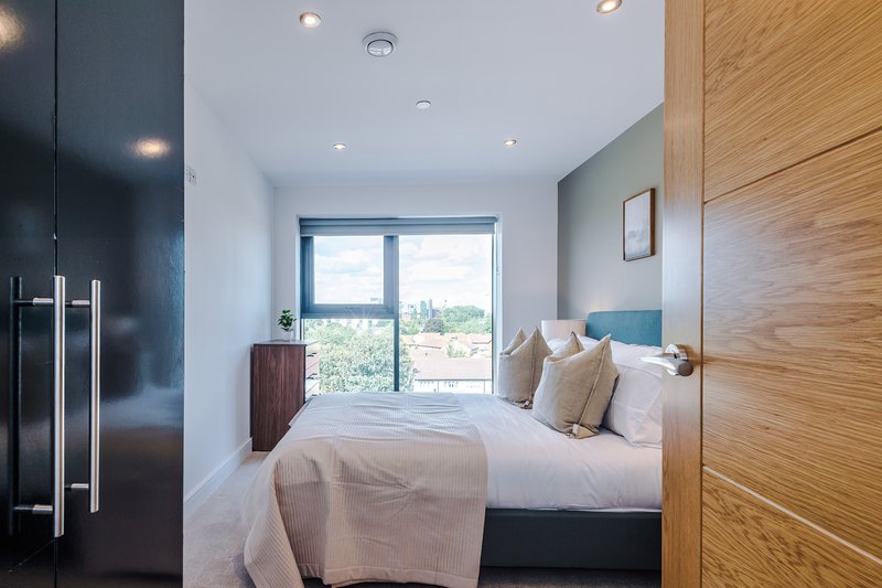 Modern bedroom with double bed, wooden wardrobes, large window with countryside view