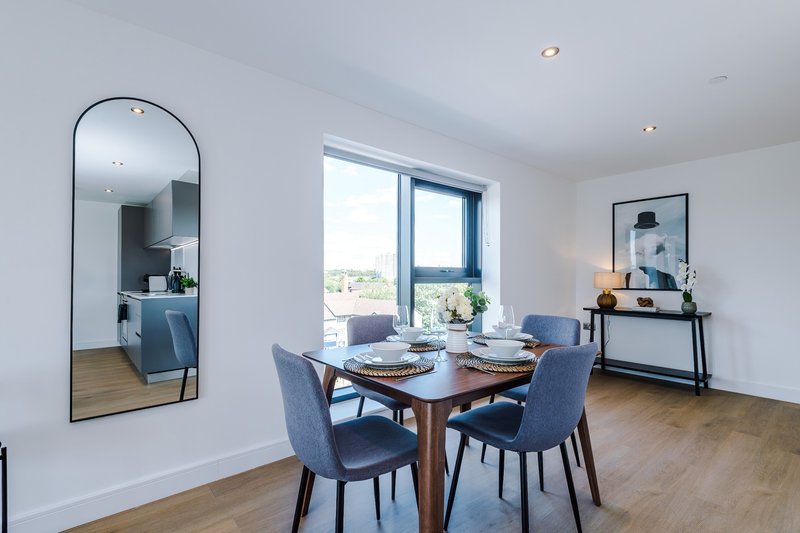 Modern dining room with wooden table, blue chairs, large mirror, and sea view windows
