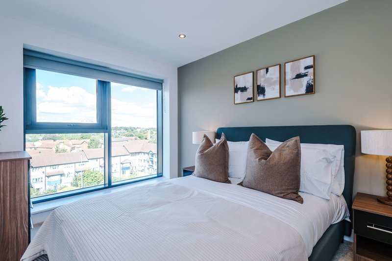 Modern bedroom with double bed, blue-framed windows, city view and wall art