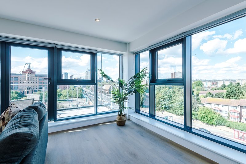 Bright corner room with floor-to-ceiling windows overlooking city skyline and green spaces