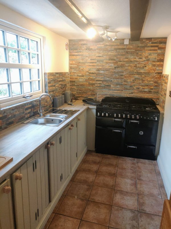 Modern kitchen with cream cabinets, brick backsplash, black range cooker and window