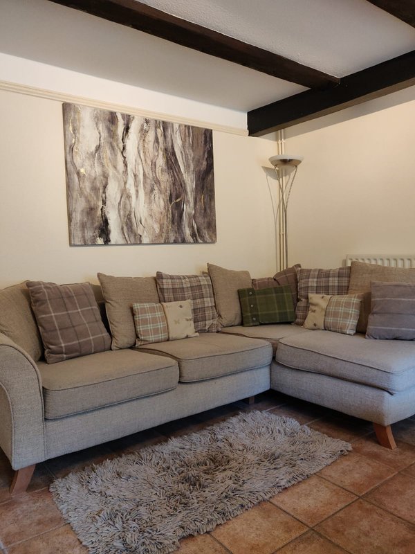 Modern living room with grey corner sofa, decorative cushions, abstract wall art and floor lamp