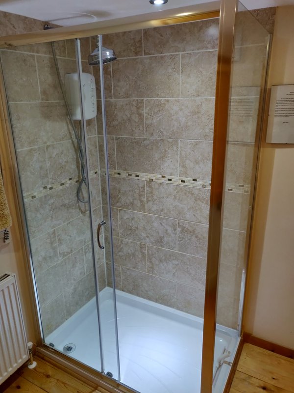 Modern bathroom with enclosed shower cubicle, tiled walls, glass doors and wooden frame
