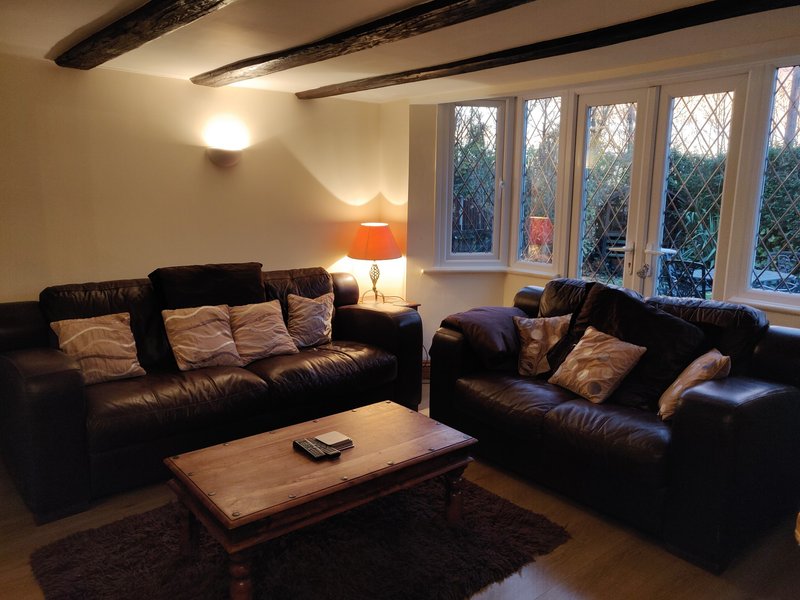 Living room with two black leather sofas, wooden coffee table, orange lamp and large windows