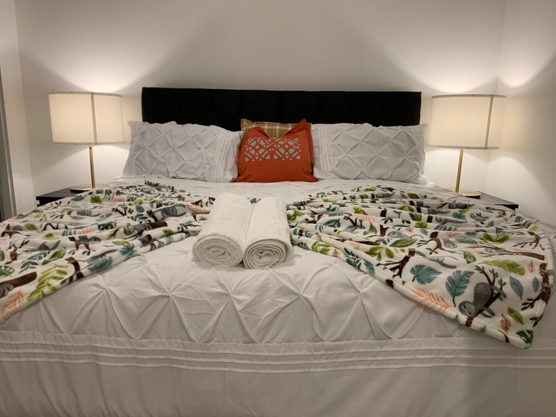 Modern bedroom with double bed, patterned bedding, decorative pillows and bedside lamps