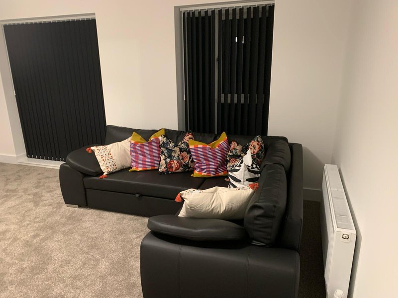 Black leather sectional sofa with colorful cushions and throws in bright living room