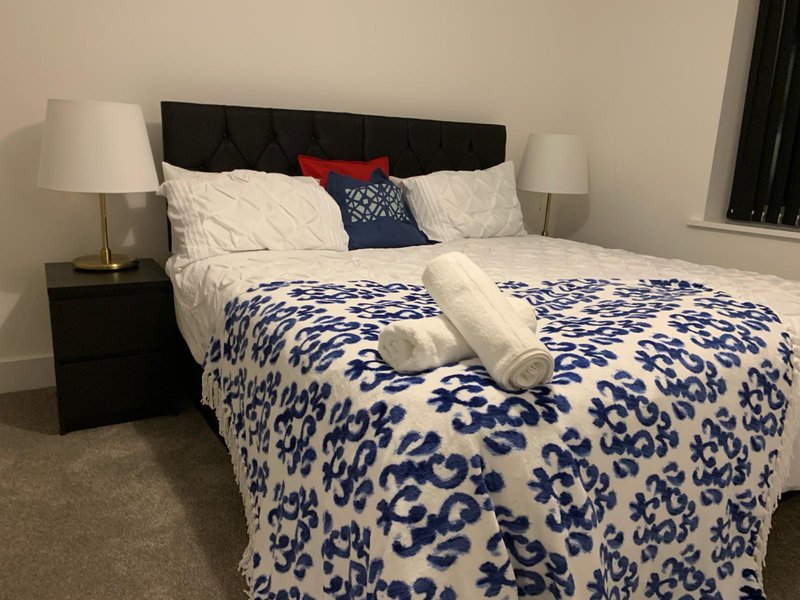 Bedroom with double bed, patterned duvet, black headboard, bedside lamps and tables