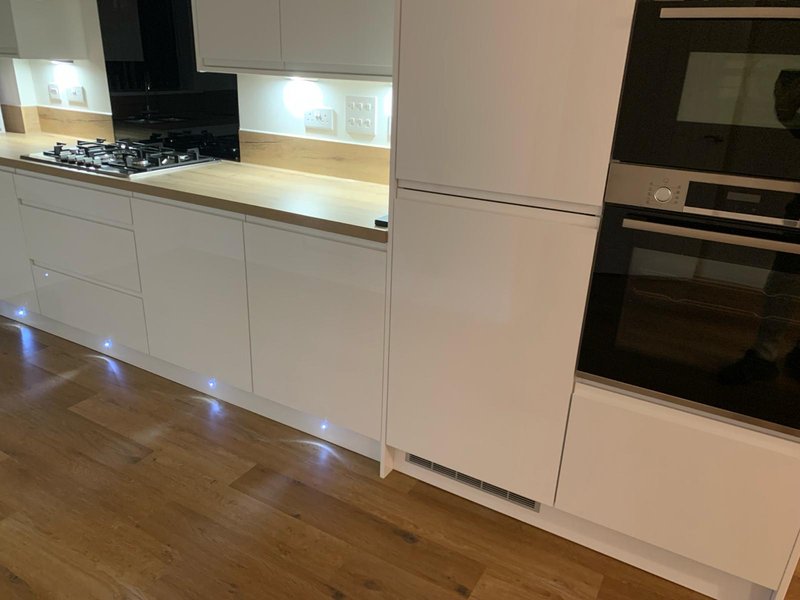 Modern white kitchen with gas hob, built-in oven, wooden worktops and wooden flooring