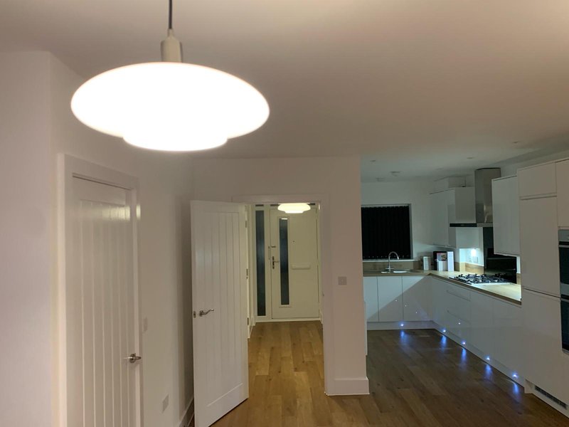 Modern open-plan kitchen and dining area with pendant light, white cabinetry, and wooden flooring