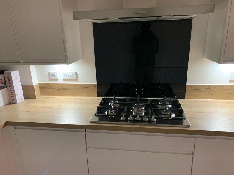 Modern kitchen with white cabinetry, wooden countertop, gas hob and black splashback