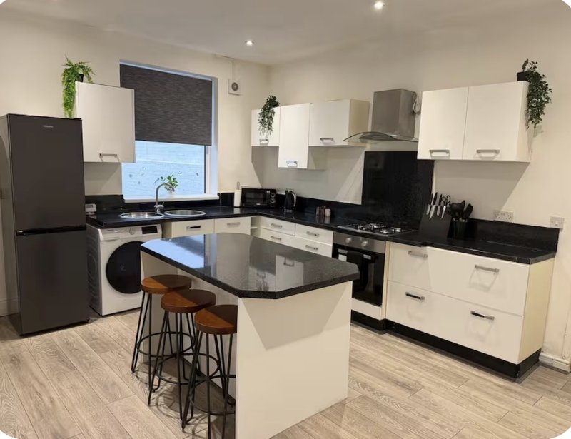 Modern kitchen with white cabinets, black countertops, island seating, and stainless steel appliances