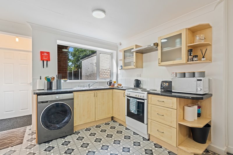 Modern kitchen with wooden cabinets, washing machine, oven, and patterned tile floor