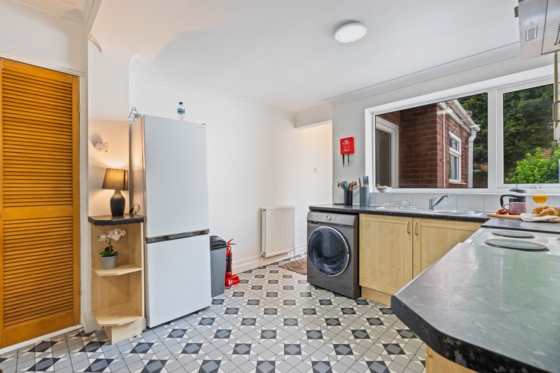 Modern kitchen with wooden cabinets, washing machine, refrigerator and patterned floor tiles