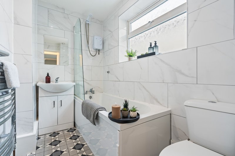 Modern bathroom with white tiles, marble accents, glass shower enclosure and bathtub