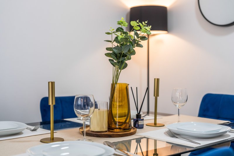 Dining table set with place settings, fresh flowers in vase, and decorative candlesticks