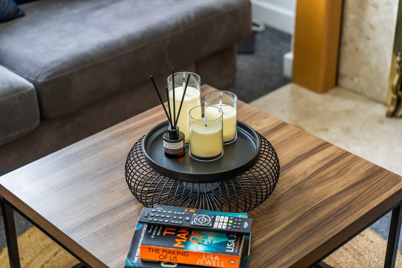 Living room coffee table with candles, reed diffuser, decorative tray, and stacked books