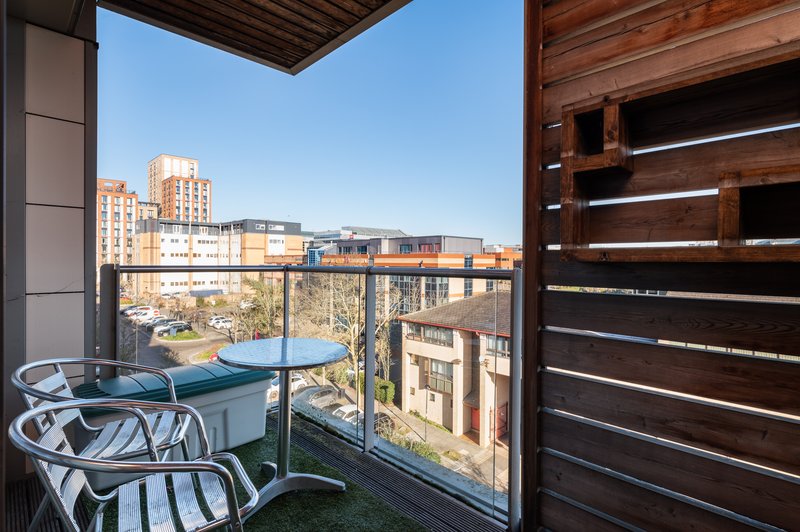 Balcony with table, chairs and city skyline view through glass railing