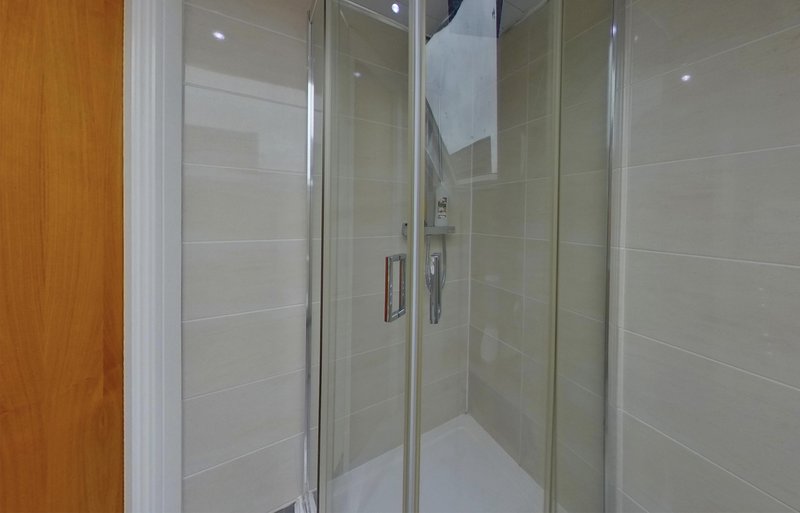 Modern bathroom with frameless glass shower enclosure and light tile walls