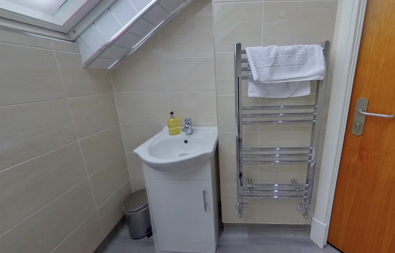 Modern bathroom with compact sink, heated towel rack, and tiled walls