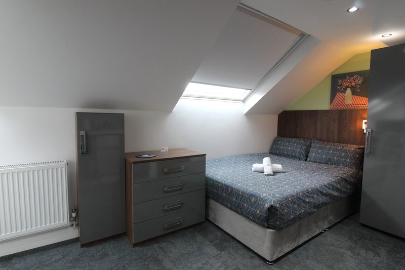 Attic bedroom with double bed, wooden dresser, skylight and radiator