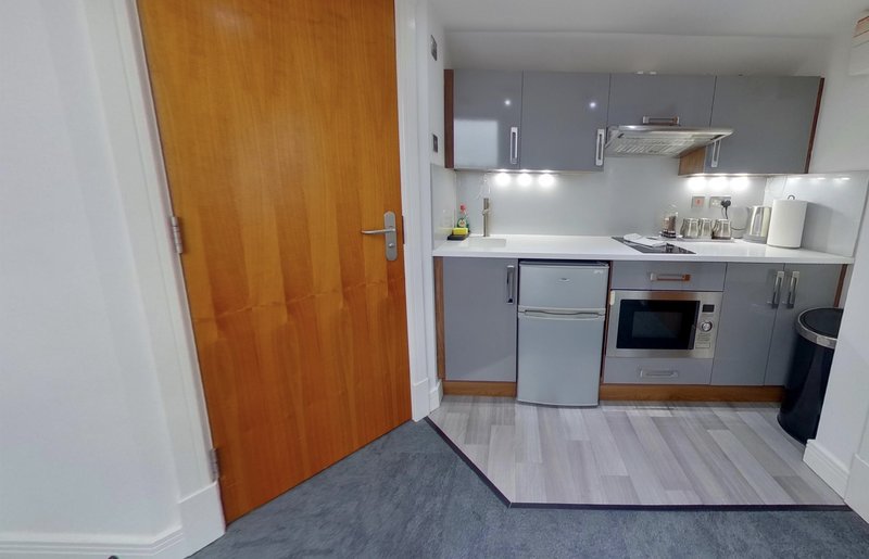 Modern kitchen with grey cabinetry, white countertop, integrated appliances and wooden door