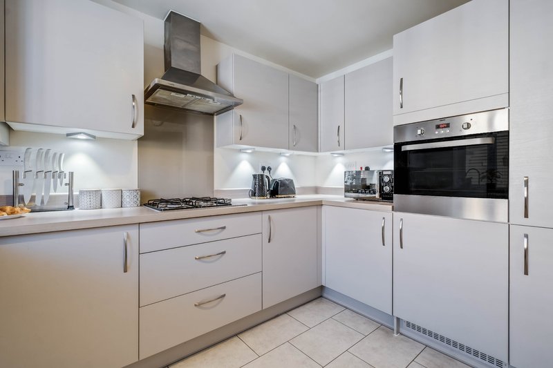 Modern white kitchen with gas hob, built-in oven, stainless steel hood and appliances