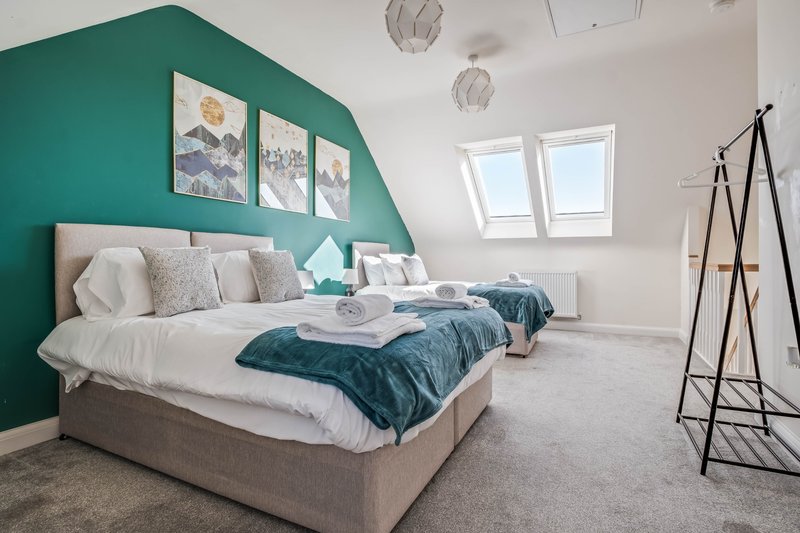 Modern bedroom with teal feature wall, double bed, skylights, and contemporary decor