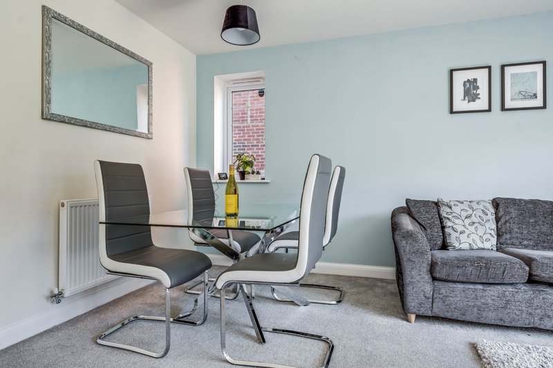 Modern living room with desk, dining chairs, grey sofa and wall mirror