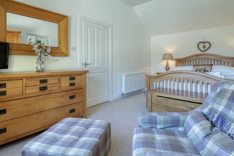 Bright bedroom with two single beds, wooden dresser, mirror and bedside lamps