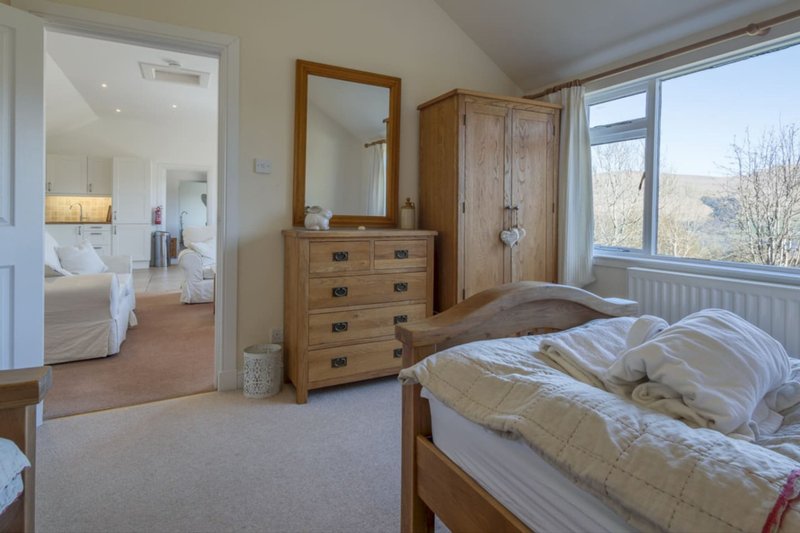 Bright master bedroom with wooden furniture, ensuite entrance, large windows and countryside views