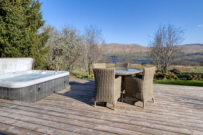 Outdoor deck with hot tub, dining table, and mountain landscape view